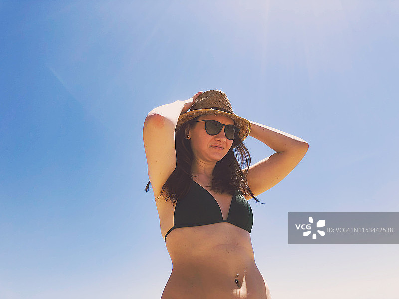 在巴塞罗那海滩和蓝天下戴帽子的快乐俄罗斯女人图片素材