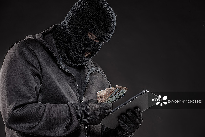 戴帽衫的未知网络罪犯，手持现金图片素材