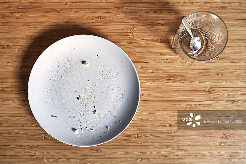 竹木桌子上带有面包屑的空盘子和空咖啡杯图片素材