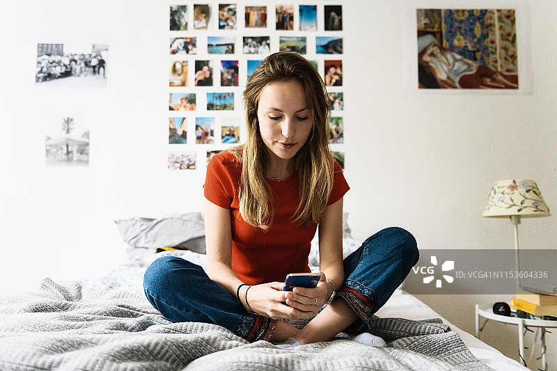 年轻女人在床上看手机图片素材