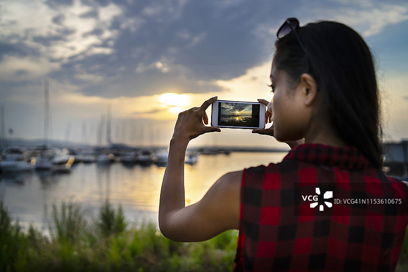 女人在日落时拍摄海港图片素材