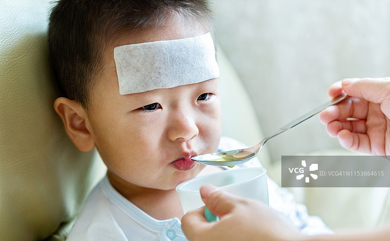生病的小男孩从母亲那里服用药物糖浆图片素材