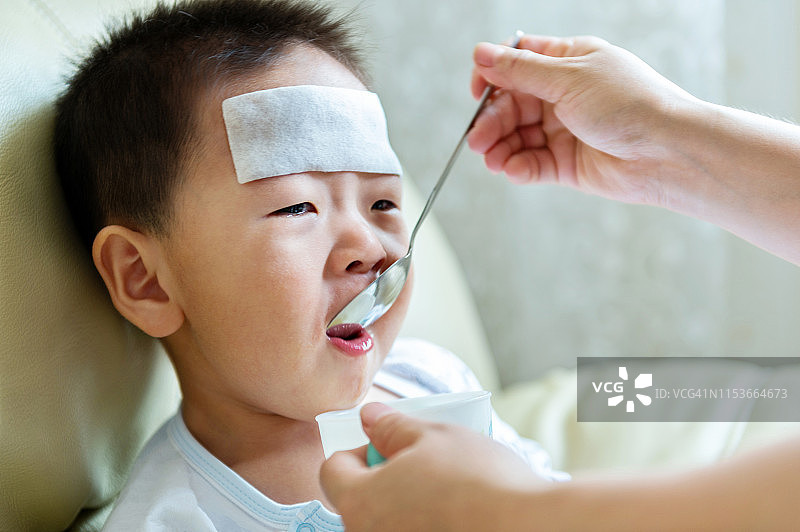 生病的小男孩从母亲那里服用药物糖浆图片素材