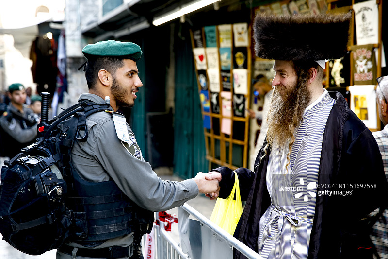 在以色列东耶路撒冷控制点，东正教犹太人与边防警察握手图片素材
