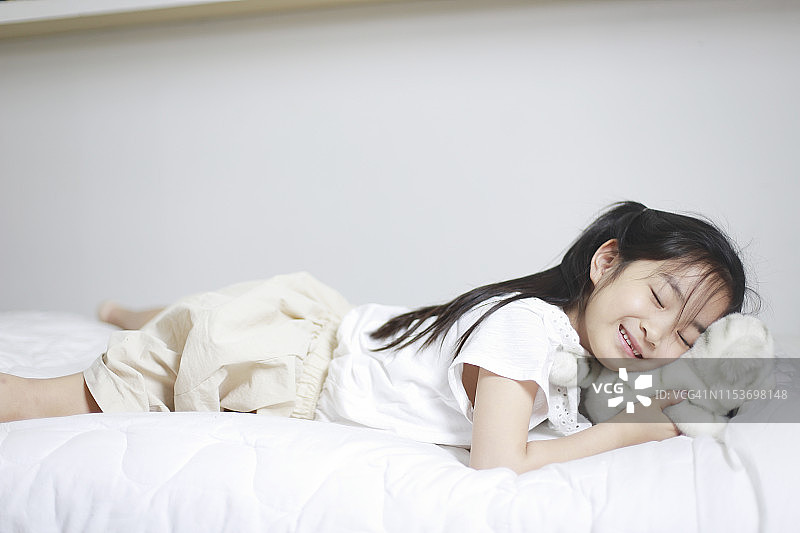 女孩在卧室里抱着娃娃睡觉图片素材