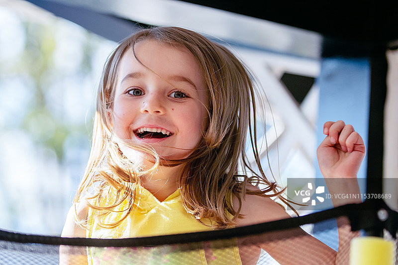 小女孩在蹦床上跳跃图片素材