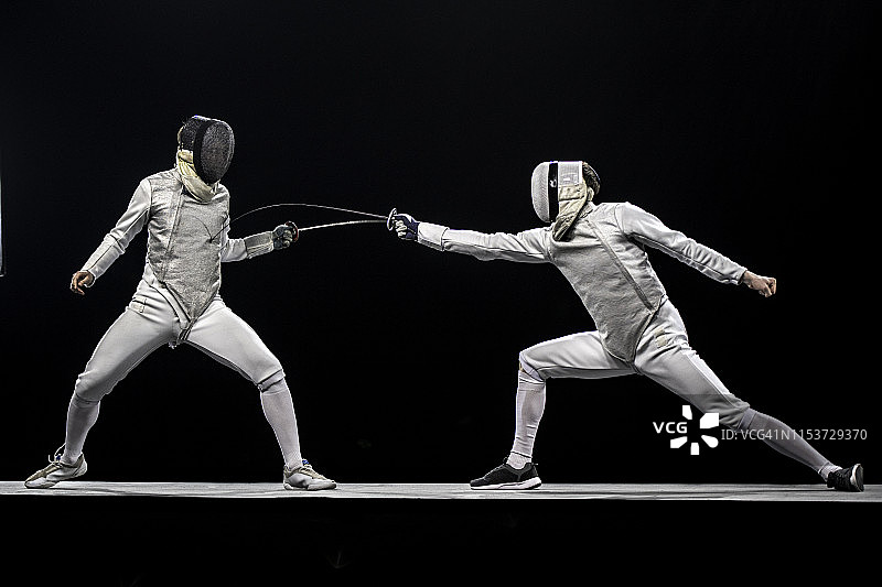 两位击剑手在黑色背景前战斗图片素材