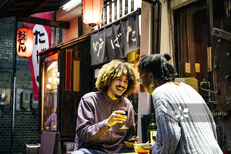 迷人的情侣在日式餐厅外端着酒杯欢笑图片素材