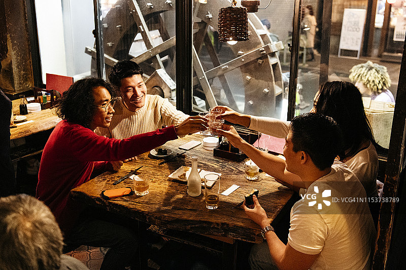 四位朋友在餐厅餐桌旁举杯庆祝的抓拍图片素材