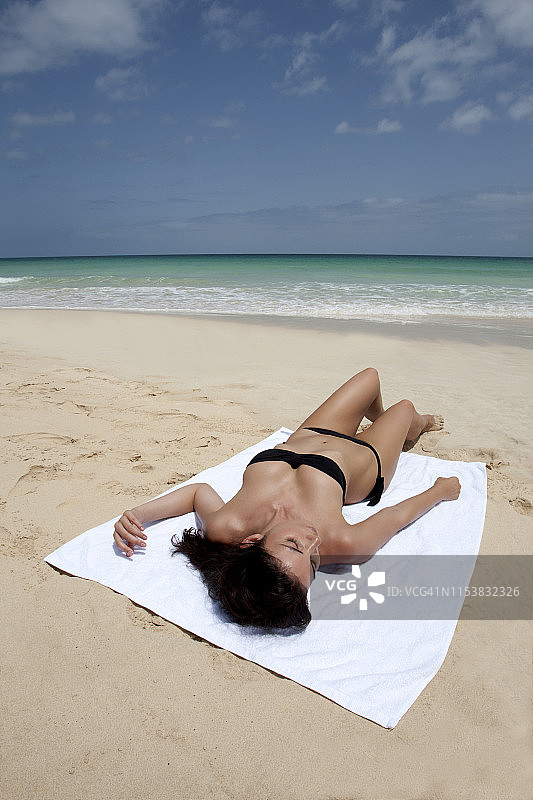 在海滩上晒日光浴的比基尼女郎图片素材