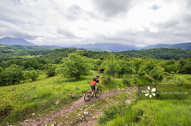 山地自行车手在阴沉的天气中穿越翠绿的乡村图片素材