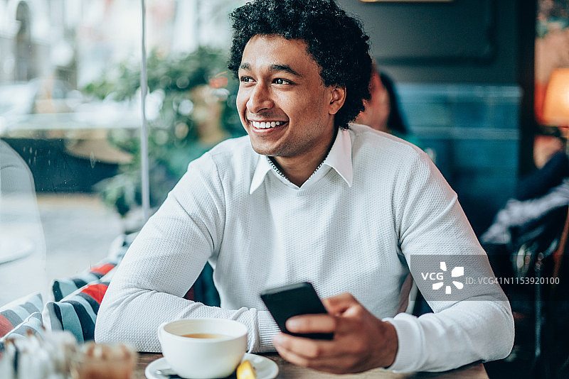 一个美国黑人，一边喝茶一边玩手机图片素材
