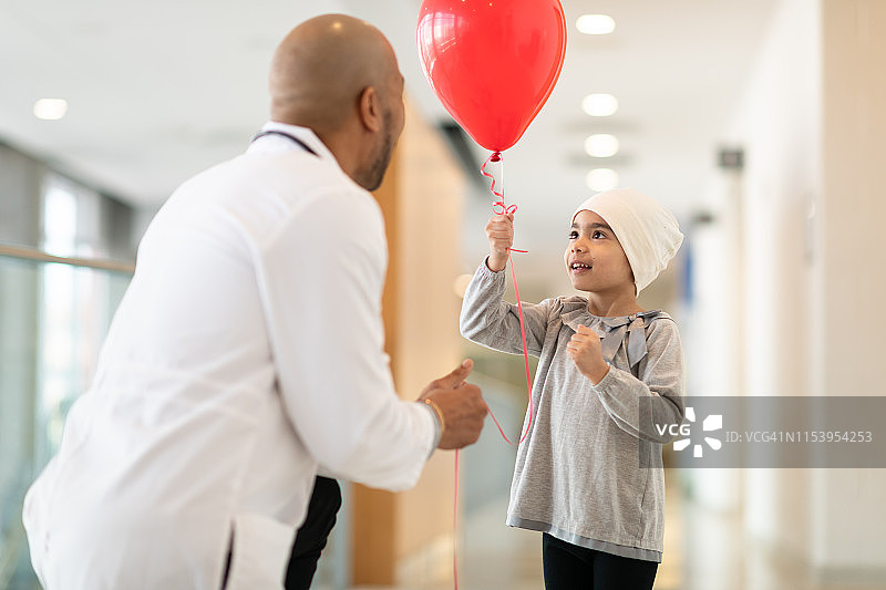 医生给患癌症的小女孩一个红色气球图片素材