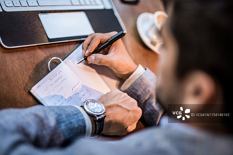 正在笔记中写计划的年轻商人图片素材