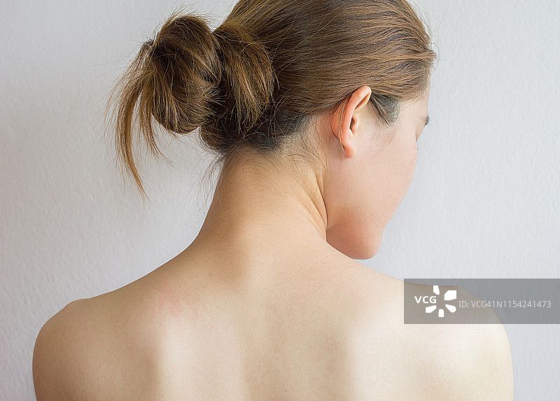 年轻女人背对镜头，在白色背景下保持裸体图片素材