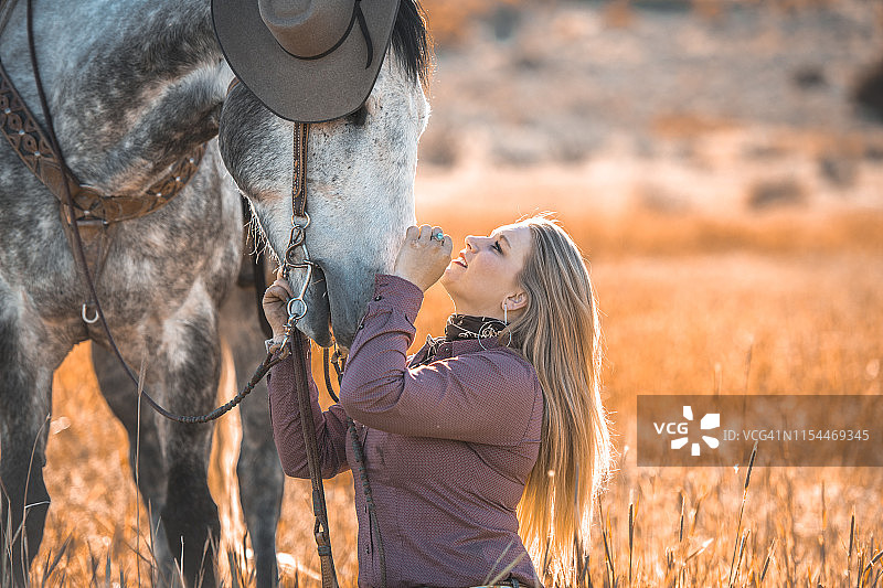 犹他州草原上的西部女骑手与花斑灰马图片素材