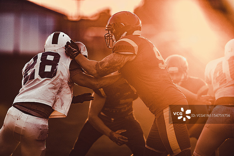 夕阳下的橄榄球进攻拦截图片素材