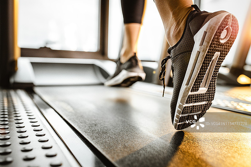 一位运动员在健身房跑步机上跑步的特写图片素材
