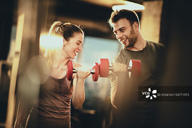 快乐的运动情侣在健身房用哑铃锻炼图片素材