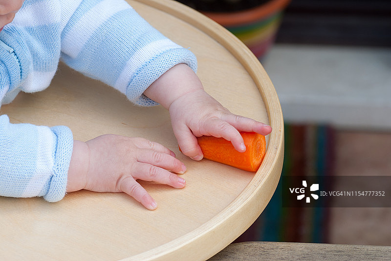 试图抓住胡萝卜的男婴图片素材