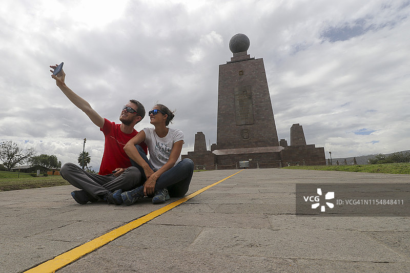 情侣在厄瓜多尔赤道纪念碑的半球分界线上自拍图片素材