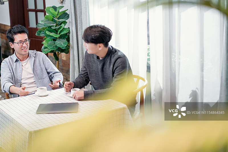 两名喝着咖啡交谈的年轻男性朋友图片素材