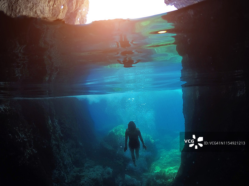 漂亮的女孩在水下洞穴中游泳。在海边度假图片素材