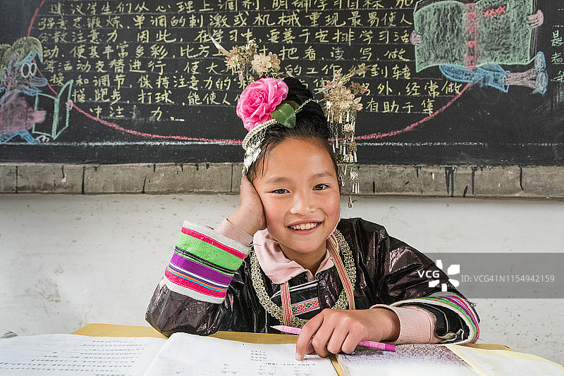 在学校教室教师桌旁就坐的侗族女孩图片素材