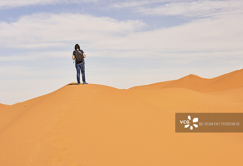 女子在摩洛哥撒哈拉沙漠的沙丘上欣赏风景图片素材