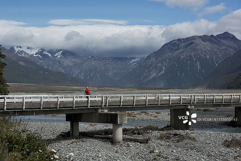 站在桥上挥手的女人，位于新西兰南岛的阿瑟隘口国家公园图片素材