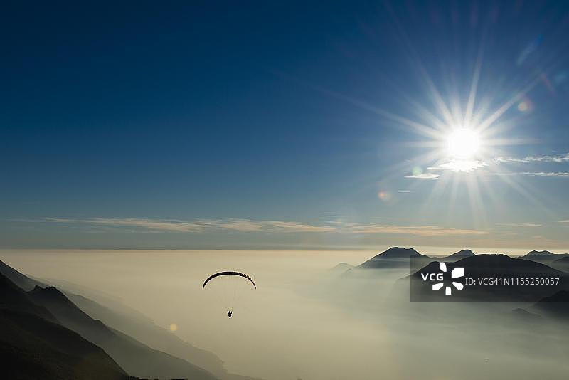 加尔达湖马尔切西内附近的云雾山脉滑翔伞航拍，意大利威尼托图片素材