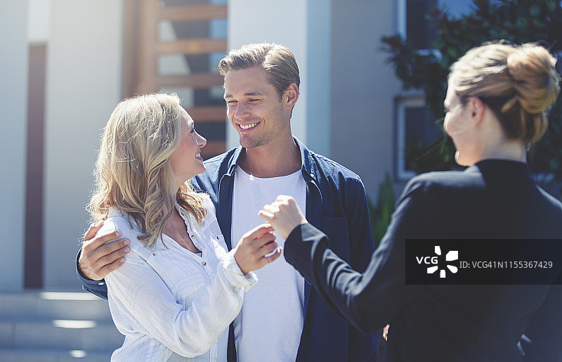 房地产经纪人将新房钥匙交给年轻夫妇图片素材