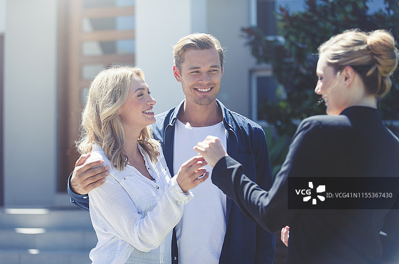 房地产经纪人将新房钥匙交给年轻夫妇图片素材