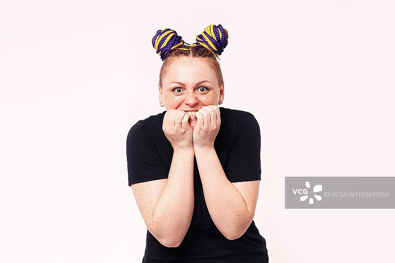 焦虑的女人咬着指甲，面露压力，看向镜头的肖像。这名女人头部有脏辫，面部有雀斑。室内工作室拍摄，白色背景。图片素材