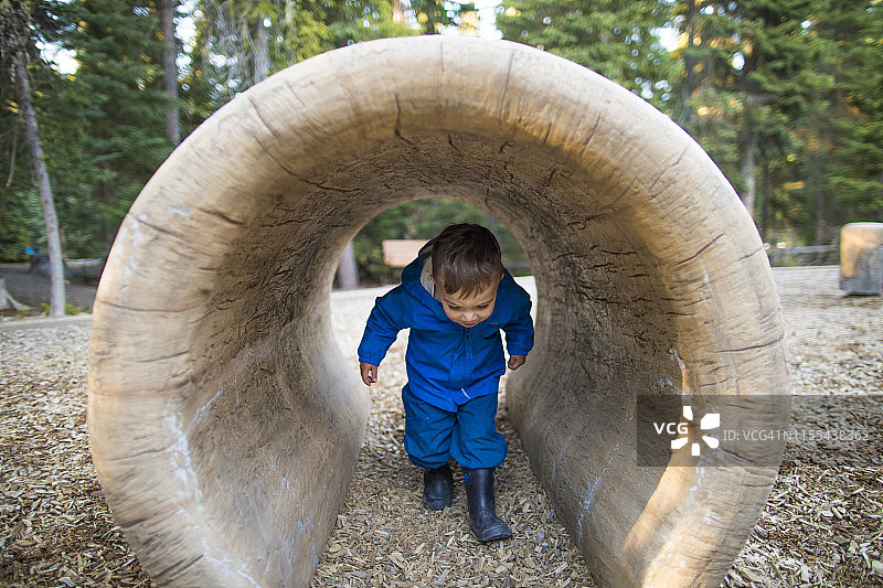 在游乐场隧道中行走时弯腰的男孩图片素材