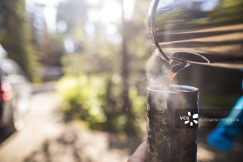 在户外将新鲜咖啡倒入旅行杯中图片素材