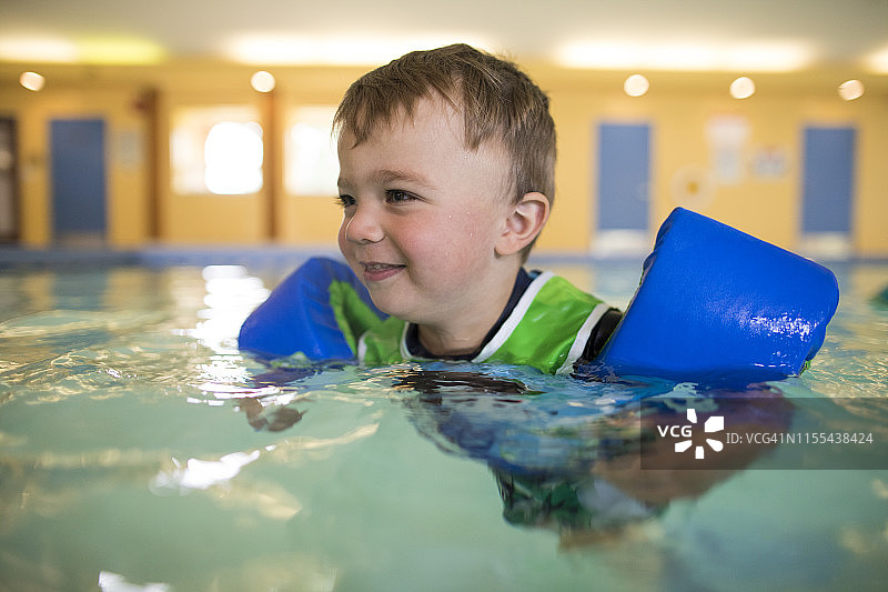 幼儿男孩戴着游泳圈游泳图片素材