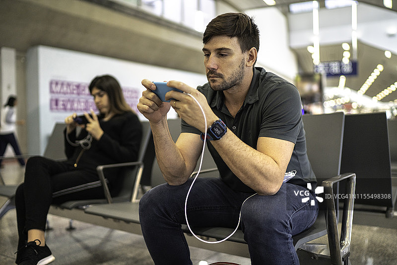男人在机场使用手机并充电图片素材