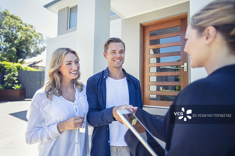 房地产经纪人将新房钥匙交给年轻夫妇图片素材