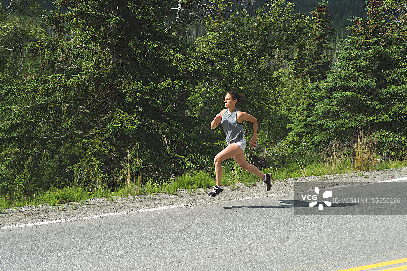 沿着阿拉斯加高速公路跑步的女慢跑者图片素材