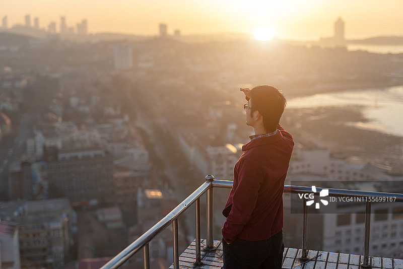 日出时分，男人在屋顶上眺望远方图片素材