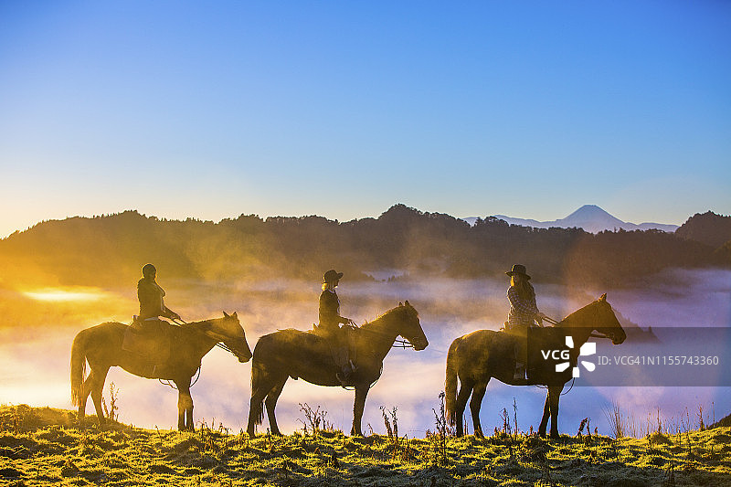 一群骑马者登上山顶观看日出图片素材
