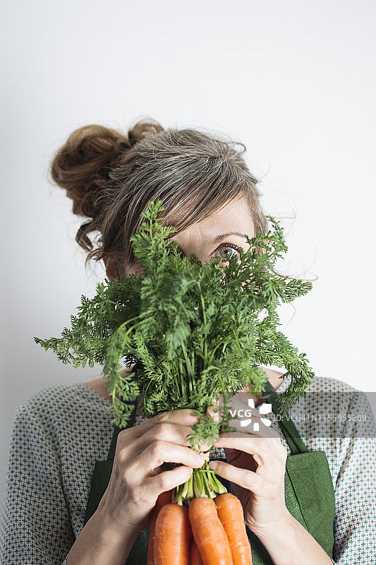 快乐的女人拿着一堆胡萝卜的肖像图片素材