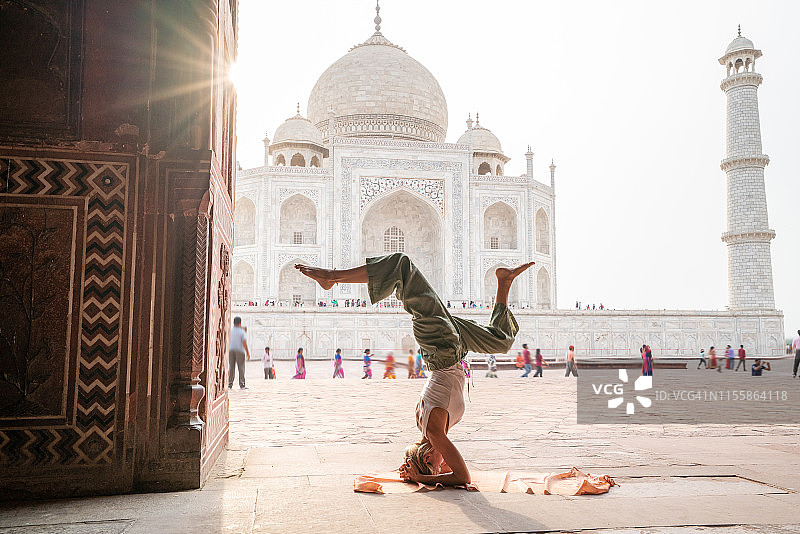 年轻女人在印度著名的泰姬陵日出时练习瑜伽——头倒立姿势图片素材