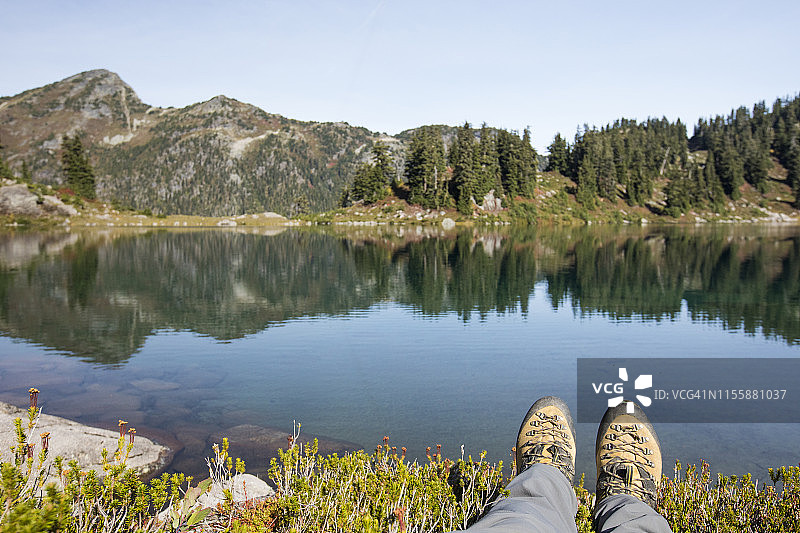 加拿大不列颠哥伦比亚省宁静的高山湖泊前的徒步靴图片素材