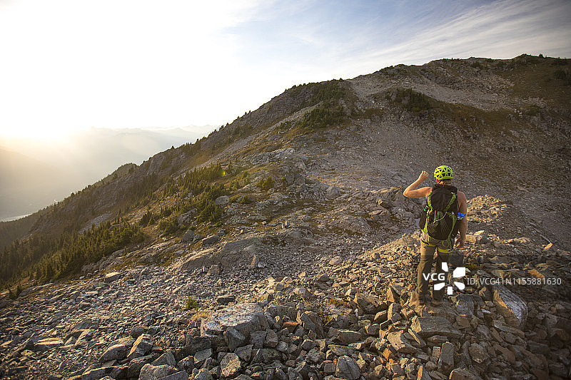 背包客在傍晚徒步时用手遮挡阳光图片素材
