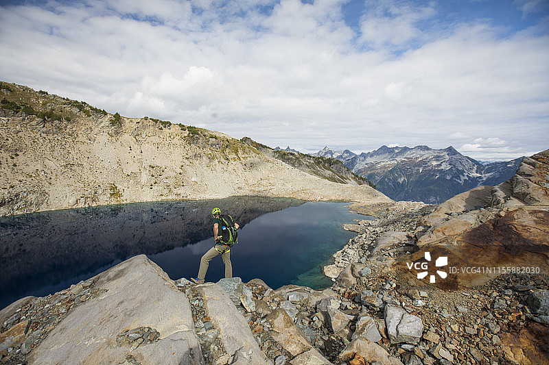 背包客站在加拿大不列颠哥伦比亚省冰斗湖上方的背影图片素材