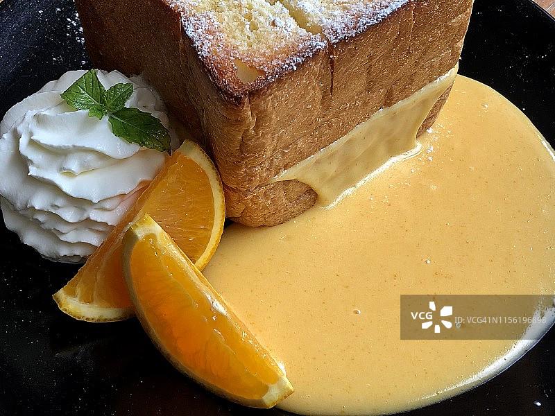 烤面包与蛋黄熔岩酱，橙子片和白色搅打奶油装饰特写图片素材