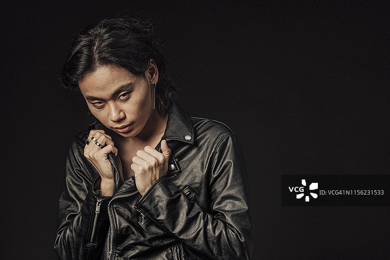 穿着皮夹克的中国男子看着镜头，半身像图片素材