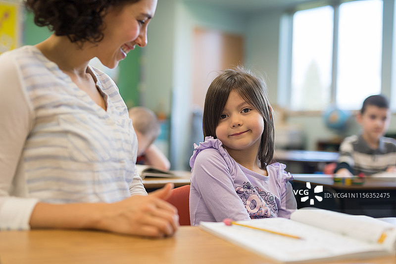 一年级女生在教室里和老师交谈图片素材